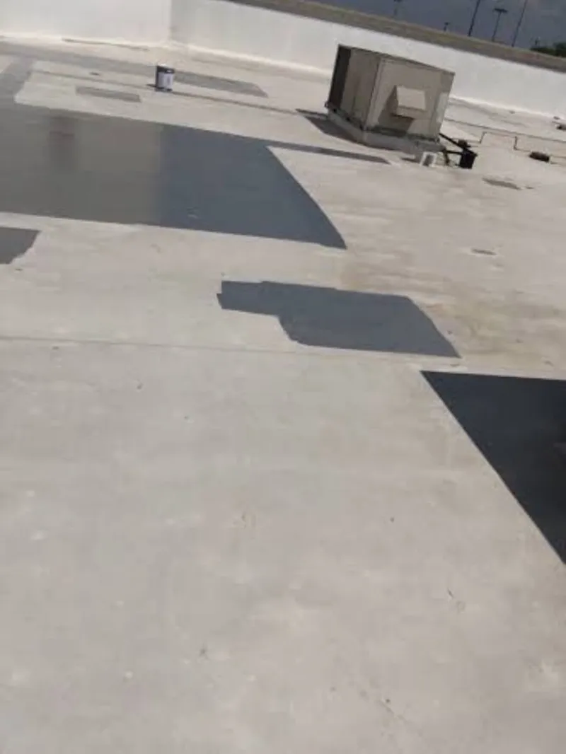 Roofing technician inspecting a flat commercial roof membrane for tears and ponding water in Austin