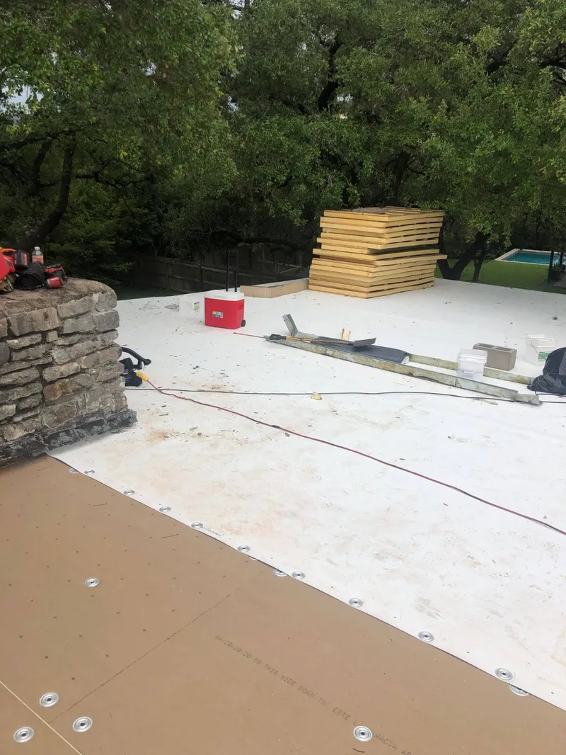 Stretching and aligning rolls of white TPO membrane across a large warehouse roof