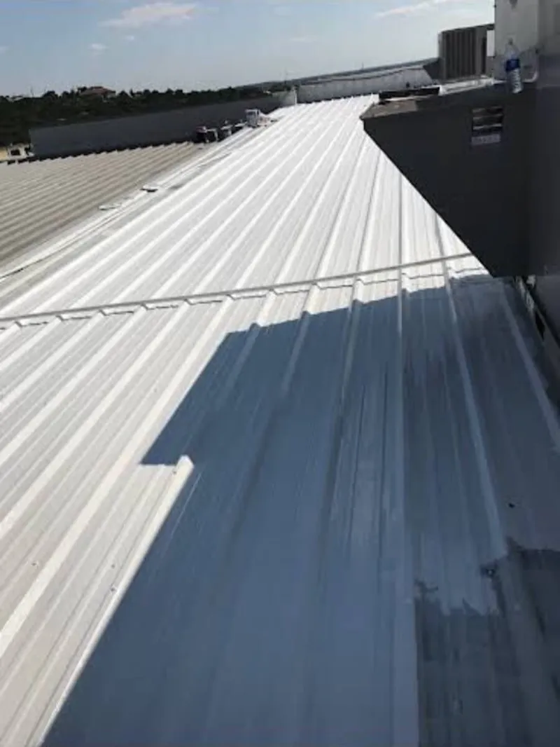 Restored commercial standing seam metal roof after application of white elastomeric cool roof system